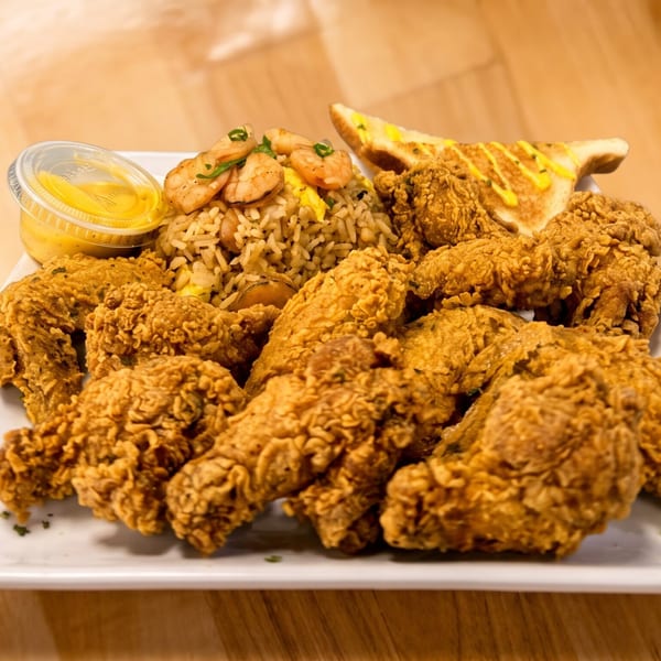A white platter holds crispy fried chicken, shrimp fried rice, toast, and a side of dipping sauce.