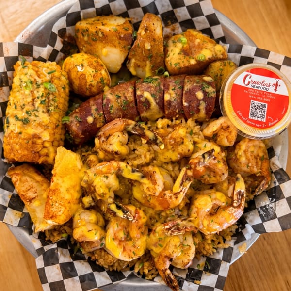 Crawlins Seafood platter with shrimp, sausage, corn, potatoes, and rice, served in a metal bowl.