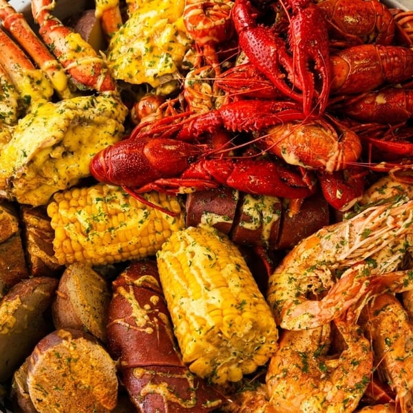 A large platter of seafood boil with crab legs, crawfish, shrimp, corn, and potatoes.